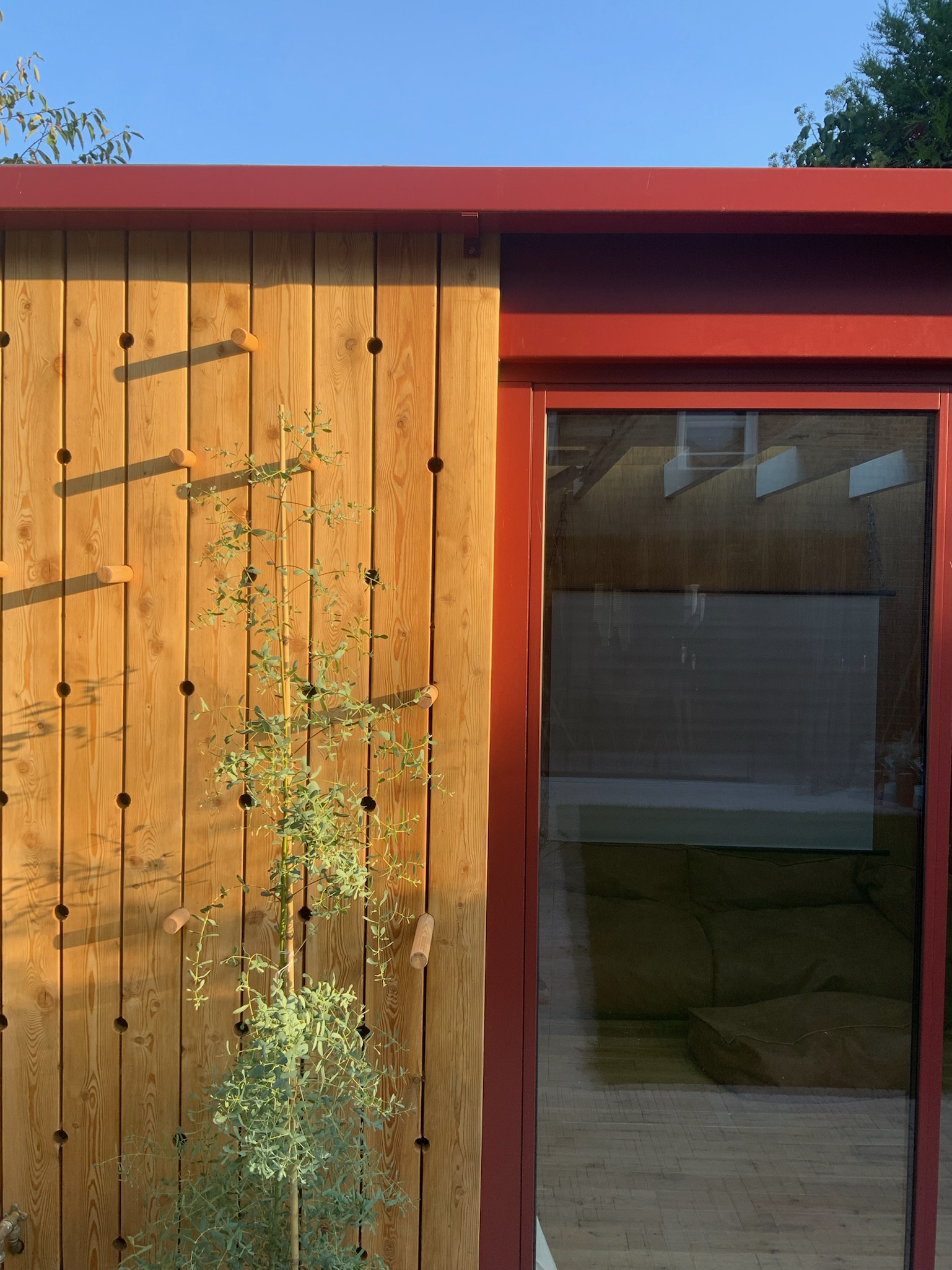 The materials palette is natural and tactile: oak timber flooring, European larch cladding, and a limestone patio provide warmth and texture. Powder-coated aluminium features and door frames in a soft oxide red take their cue from the Acer tree in the garden. Underfloor heating ensures comfort year-round.</p>
<p>The design was carefully considered to meet the needs of a young family while retaining a calm, open feel and an attractive aesthetic when viewed from the house.