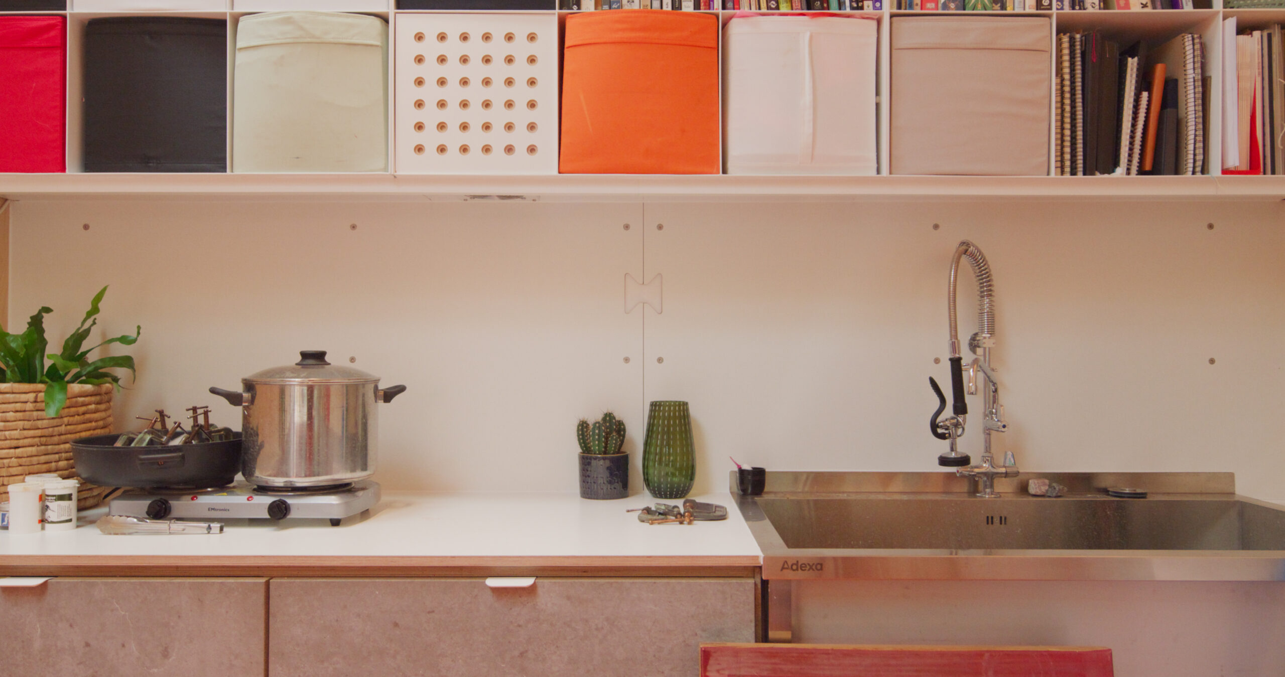 The exterior features vertically oriented burnt larch cladding, punctuated by powder-coated metal capping and window reveals, providing a refined contrast to the natural surroundings. Inside, vibrant, durable finishes balance warmth with bold colour, fostering inspiration without compromising functionality. A large stainless steel sink and generous work surfaces meet the practical demands of dyeing and fabric design.</p>
<p>This garden studio is a carefully considered space where light, materiality and functional planning support both creativity and daily work. The result is a dynamic, serene environment that invites exploration and craftsmanship.