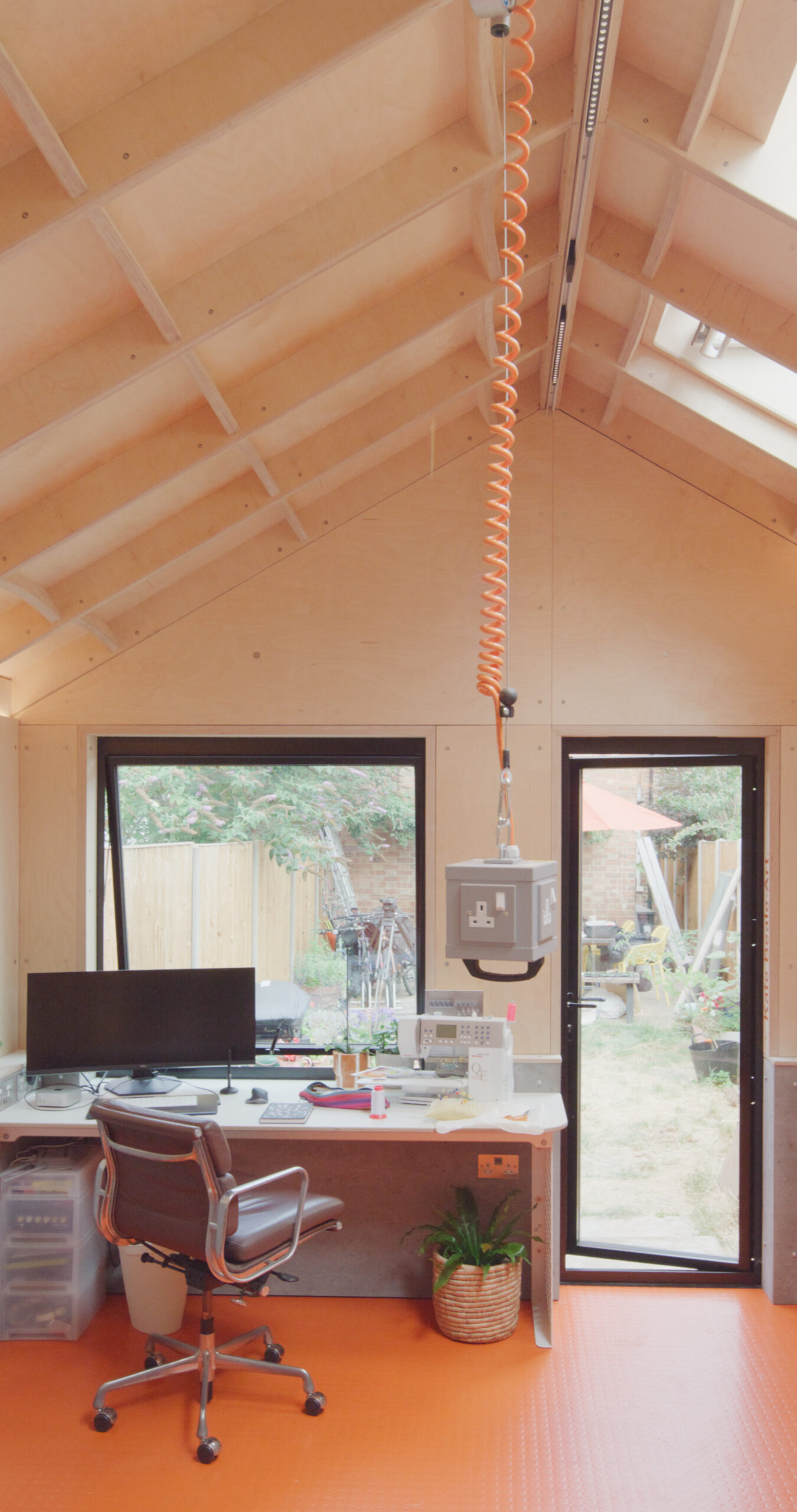 The exterior features vertically oriented burnt larch cladding, punctuated by powder-coated metal capping and window reveals, providing a refined contrast to the natural surroundings. Inside, vibrant, durable finishes balance warmth with bold colour, fostering inspiration without compromising functionality. A large stainless steel sink and generous work surfaces meet the practical demands of dyeing and fabric design.</p>
<p>This garden studio is a carefully considered space where light, materiality and functional planning support both creativity and daily work. The result is a dynamic, serene environment that invites exploration and craftsmanship.